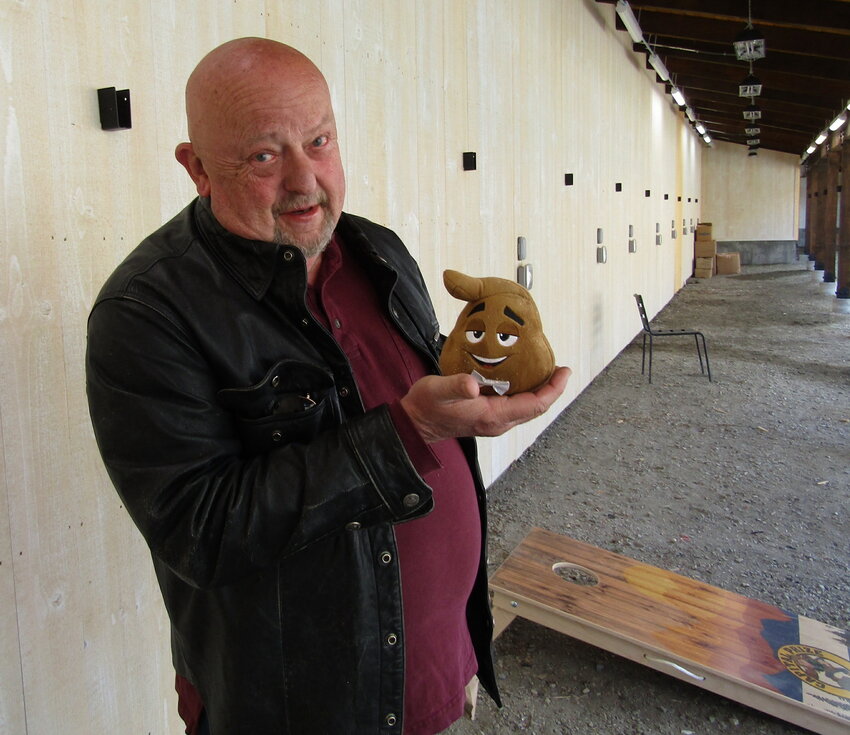 Robert Smith, president of Clear Creek Rotary 2000, stands next to the “pitch poop” cornhole game with one of the bags that add to the game fun.